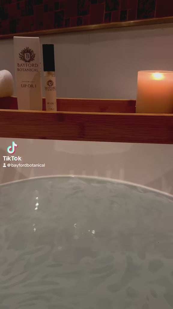 Bayford Botanical LIP OIL I beside a candle during a relaxing bath ritual.
